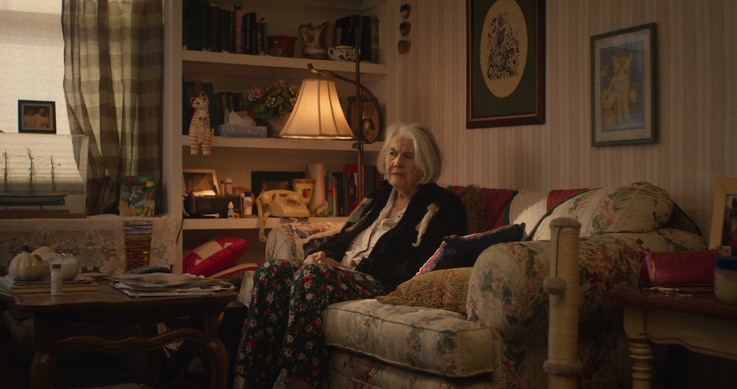 Lois Smith sits on a couch in a house
