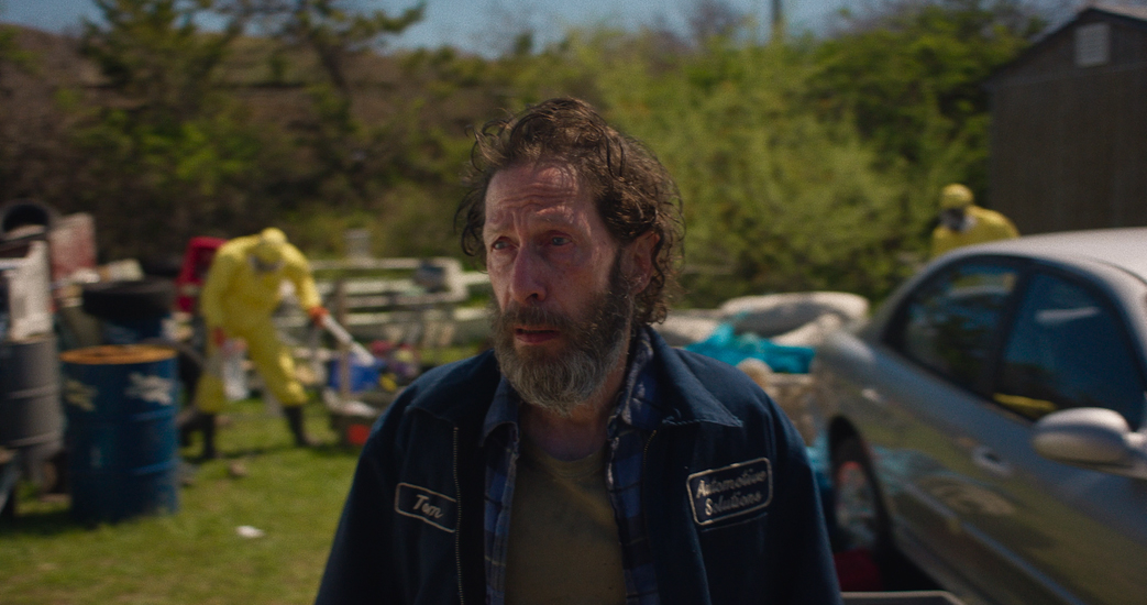 Tim Blake Nelson stands in a yard